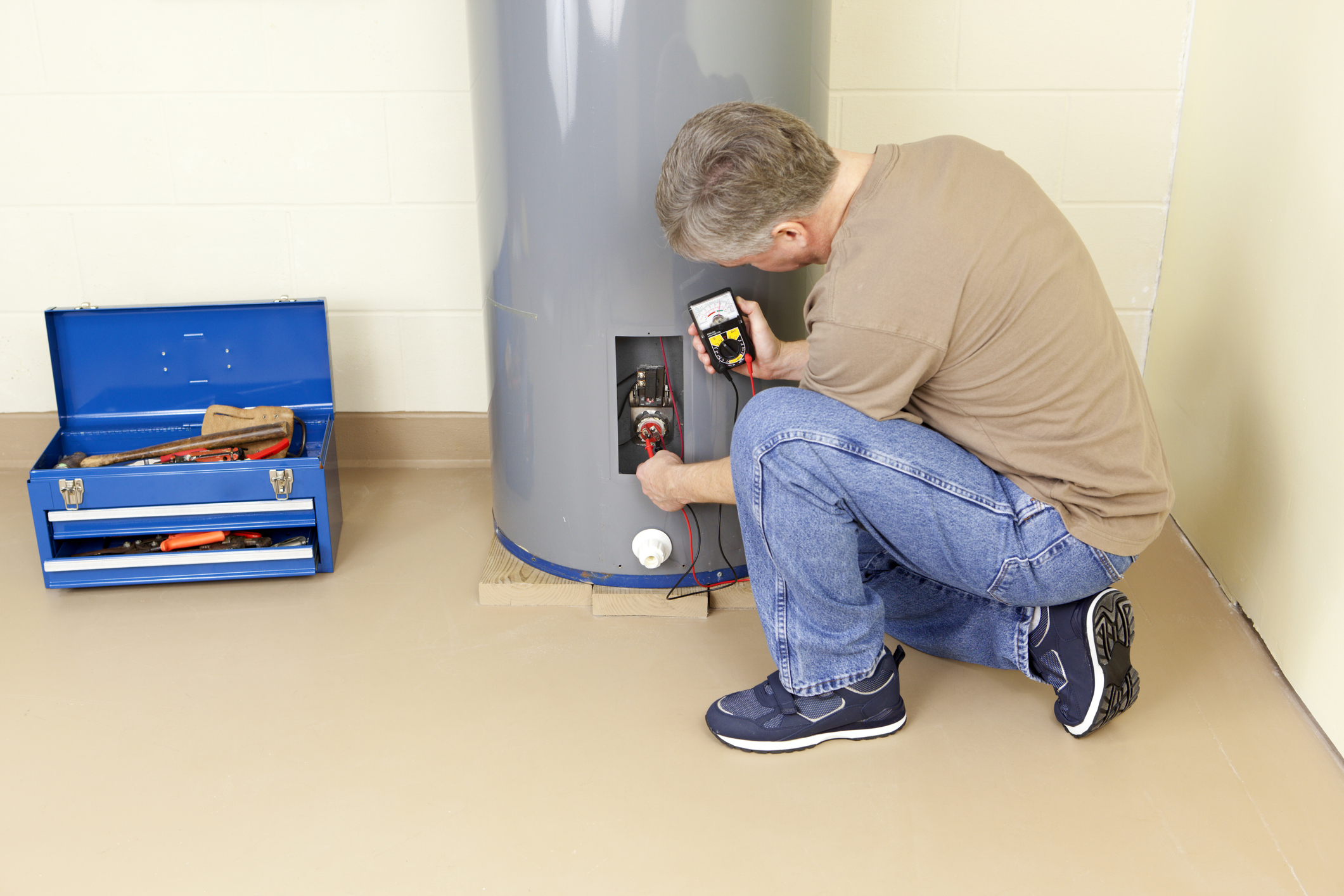 Plumber testing water heater element with analog multimeter