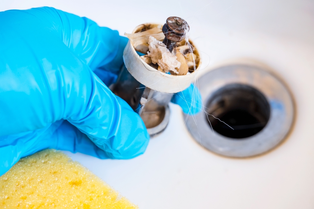 Plumber inspecting a garbage disposal humming but not spinning after a summer BBQ